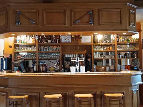 a bar with wooden cabinets and bar stools at Auberge le Cévenol in La Cavalerie