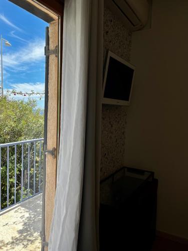 une porte donnant sur un balcon avec une télévision et une fenêtre dans l'établissement Hotel Le Patio, à Théoule-sur-Mer