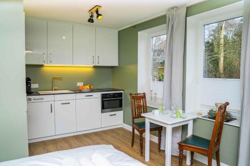 a kitchen with white cabinets and a table and chairs at Gästehaus "Alte Bücherei" Satrup in Mittelangeln