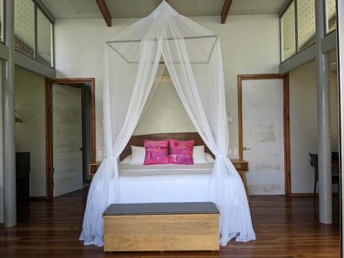 a bedroom with a canopy bed with pink pillows at Cielo Lodge in Golfito