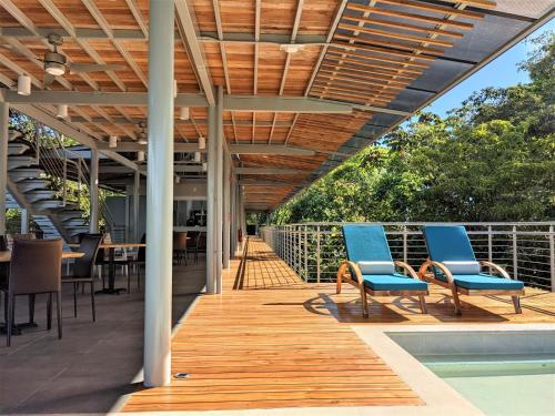a deck with blue chairs and a table and a pool at Cielo Lodge in Golfito