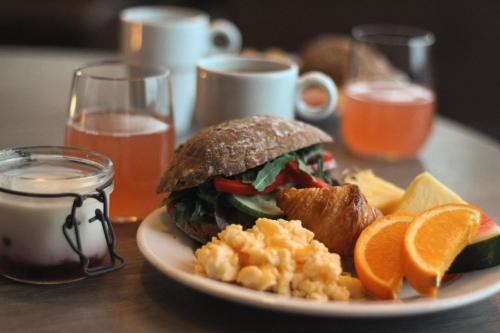 a plate of food with a sandwich and some orange slices at Tanumstrand SPA & Resort Stugor in Grebbestad