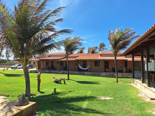 a yard with palm trees in front of a building at Pousada Recanto da Mãezinha in Beberibe