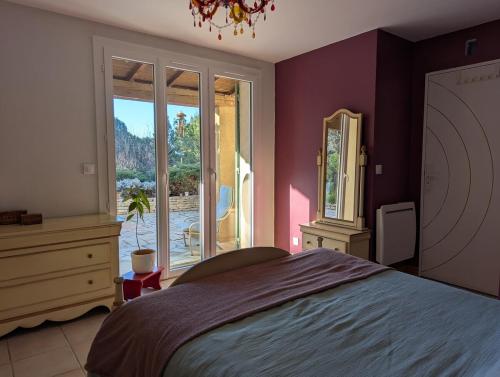 une chambre avec un lit et une grande fenêtre dans l'établissement Villa Serenité avec Piscine au Coeur du Luberon, à La Tour-dʼAigues