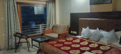 a bedroom with a bed and a chair and a window at Summer lead in Shimla