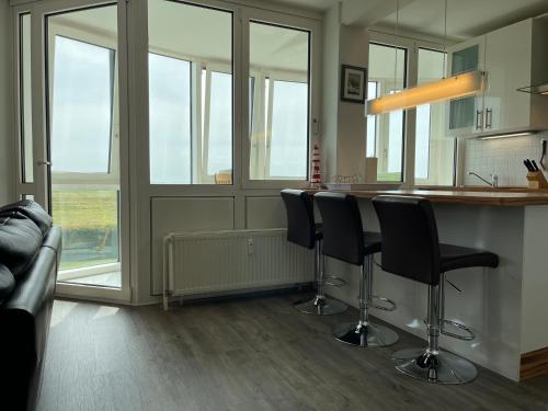 a kitchen with a bar with black chairs and windows at Apartment 12 in Wilhelmshaven