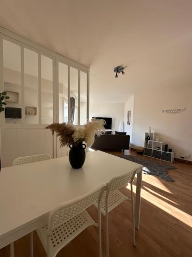 - une table à manger blanche avec un vase de fleurs dans l'établissement Repos urbain, à Saint-Brieuc