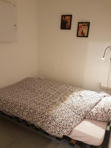 un lit dans une chambre avec deux tableaux au mur dans l'établissement BANDOL T2 HYPER CENTRE rue calme, à Bandol