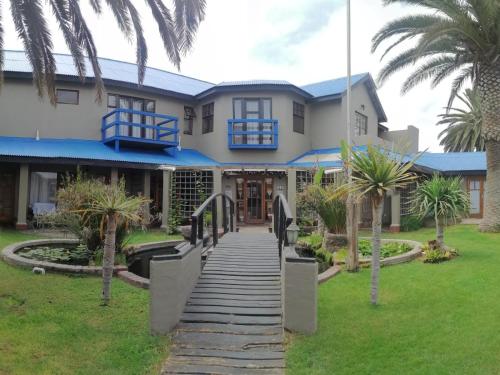 a house with palm trees in front of it at 22 on Main Guesthouse Walvis Bay in Walvis Bay