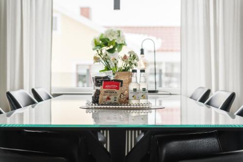 a table with a bouquet of flowers and bottles on it at Guestly Homes - Modern 4BR Villa with Sauna in Piteå