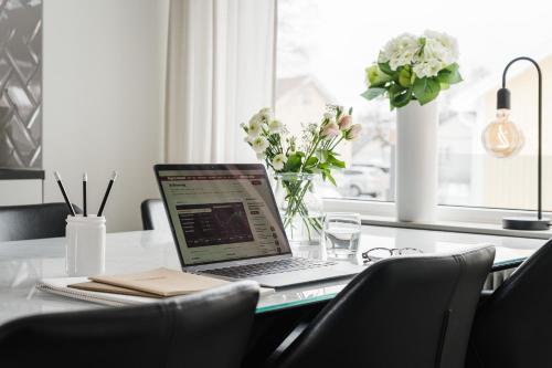 a laptop computer sitting on a table with a vase of flowers at Guestly Homes - Modern 4BR Villa with Sauna in Piteå