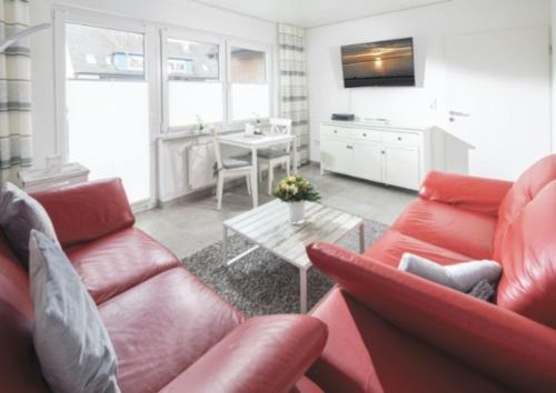 a living room with a red couch and a table at Admirals Lodge in Norddeich