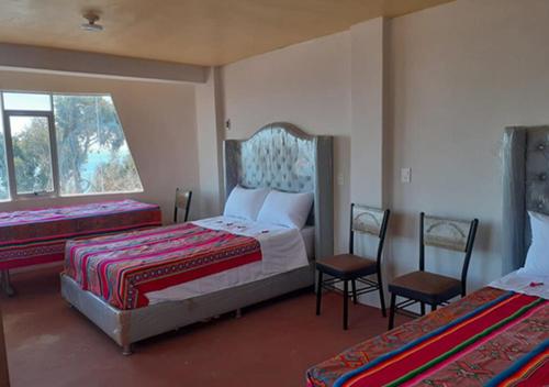 a bedroom with two beds and two chairs and a window at Inti Raymi Lodge in Escallani