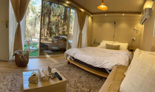 a bedroom with a bed and a large window at كرفان العلا caravan alula in Al-ʿUla