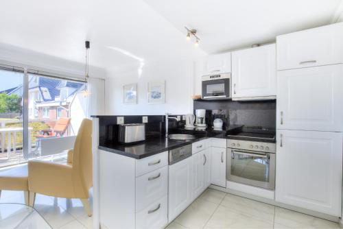 a white kitchen with white cabinets and appliances at Windeby 6E in Wenningstedt