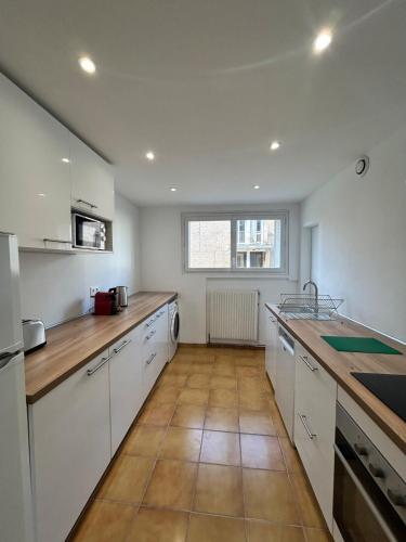 une cuisine avec des armoires blanches et un plancher en bois dans l'établissement Le Chambéry 6p parking privé clim, à Toulouse