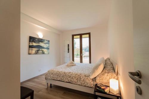 a white bedroom with a bed and a window at Como home residence in Carlazzo