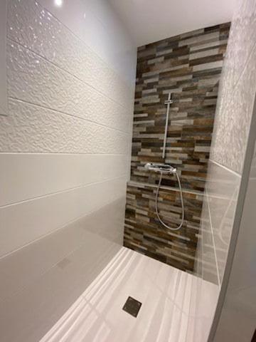 La salle de bains est pourvue d'une douche et d'un mur en pierre. dans l'établissement Villa Harmonia, à Sainte-Marie de Ré
