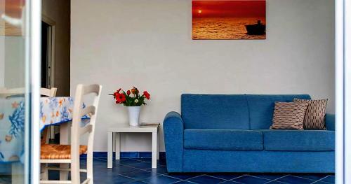 a living room with a blue couch and a table at Magico Appartamenti Scafa - Marina Capo d'Orlando in Capo dʼOrlando