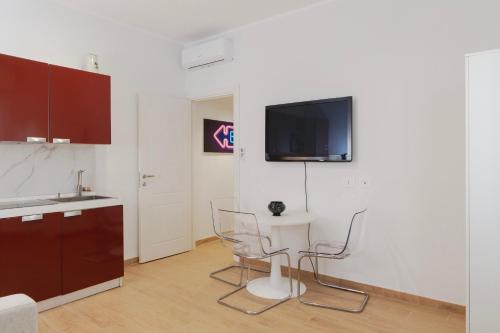 a kitchen with two chairs and a tv on a wall at Residence i Tigli in Cinisello Balsamo