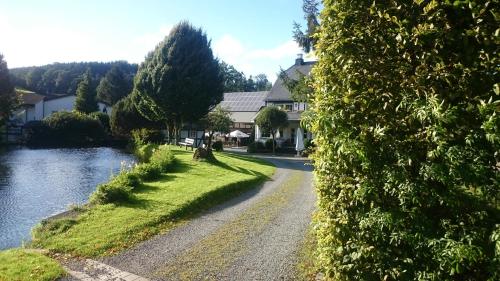 a road in front of a house next to a river at Landhof Grewen Mühle in Meschede