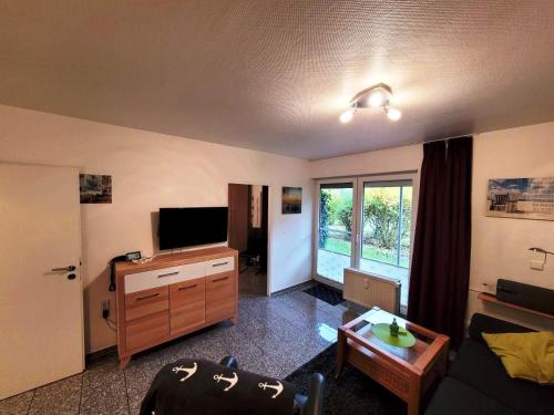 a living room with a flat screen tv and a table at Kleine Auszeit in Dorum-Neufeld