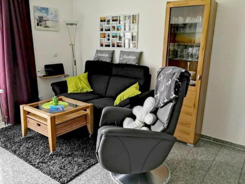 a living room with a black couch and a chair at Kleine Auszeit in Dorum-Neufeld