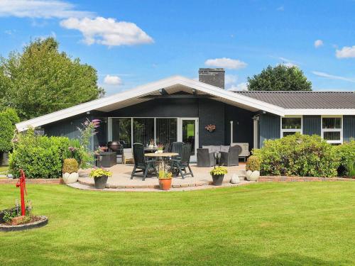 a house with a patio with a table and chairs at 8 person holiday home in Væggerløse in Bøtø By
