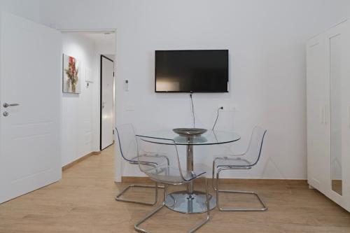 a glass table with two chairs and a television on a wall at Residence i Tigli in Cinisello Balsamo