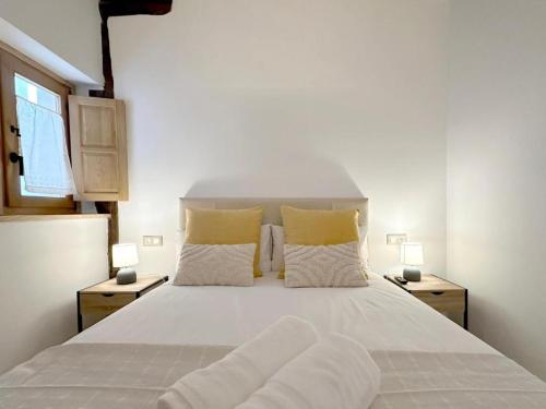 a bedroom with a large white bed with two lamps at El Patio de Vespasiano- San Juan- vistas al ayuntamiento junto al puerto in Castro-Urdiales