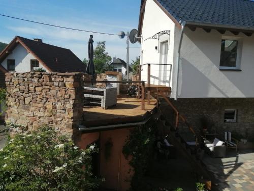 a house with a stone retaining wall and a patio at KyllHof Angelsen in Birresborn