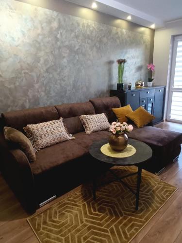 a brown couch in a living room with a table at Apartament Ełk Tuwima 5 in Ełk