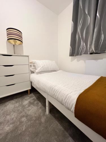 a white bedroom with a bed and a dresser at Private Cosy Room in Barking