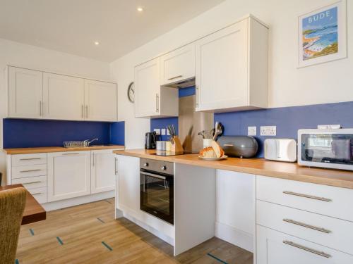 a kitchen with white cabinets and a counter top at Tommy Jacks Beach Apartments in Bude