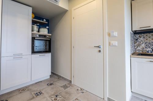 a kitchen with white cabinets and a tile floor at Domus Mea in Forza dʼAgro