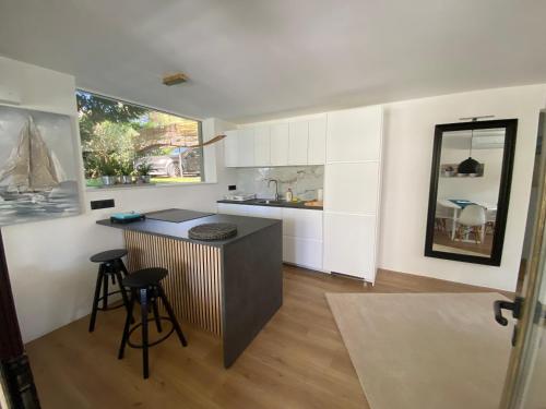 a kitchen with white cabinets and a counter and stools at Residence Peček in Novigrad Istria