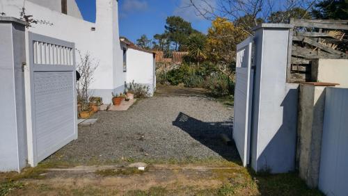 an alley with a white building and a gate at Villa Les Palmiers in Saint-Jean-de-Monts