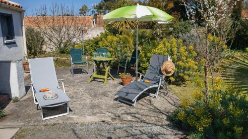 a patio with a table and chairs and an umbrella at Villa Les Palmiers in Saint-Jean-de-Monts