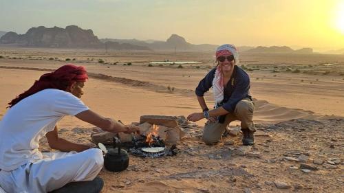 two women sitting around a fire in the desert at Ahmad and Fatima's Traditional Bedouin Camp in Al Ḩumaymah al Jadīdah