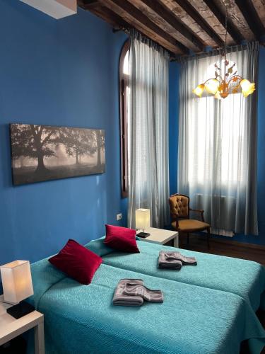 a blue bedroom with a large bed with red pillows at TINTORETTO VISTA REAL VENICE in Venice