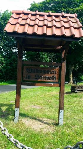 a sign sitting in the grass with a roof at Ferienwohnung Gebken in Börgerwald