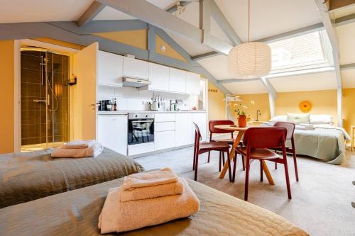a bedroom with two beds and a table and a kitchen at Familielogement De Oude Beltoren in Utrecht
