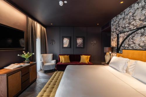 a bedroom with a large white bed and a couch at The Goethe Hotel - Small Luxury Hotels of the World in Rome