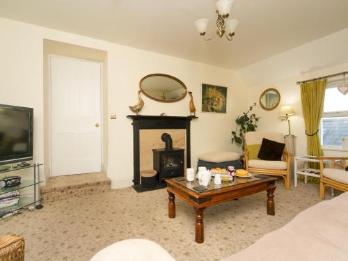 a living room with a fireplace and a table at Tyn Lon, Moelfre, A Traditional Welsh Home By The Coast Pass the Keys in Moelfre