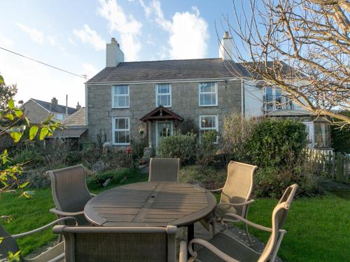 a wooden table and chairs in front of a house at Tyn Lon, Moelfre, A Traditional Welsh Home By The Coast Pass the Keys in Moelfre