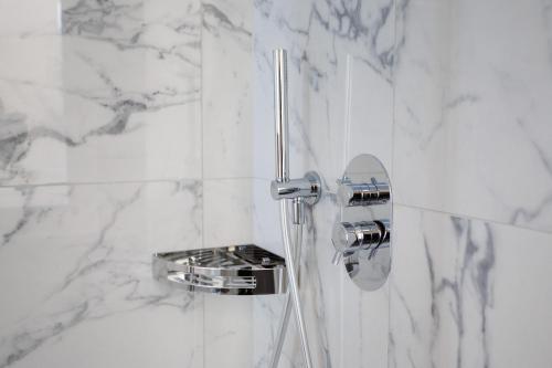 a bathroom with a shower with white marble walls at 1823 Room in Chioggia