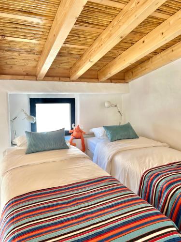 two beds in a room with wooden ceilings at Casa Sul - Casas de Seixe in Baiana