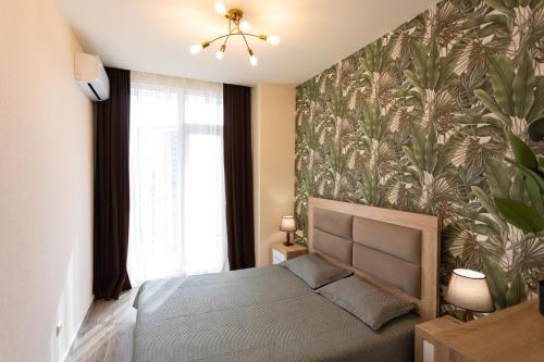 a bedroom with a bed with a tropical wallpaper at Cozy place New Boulevard in Batumi