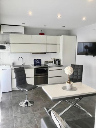 une cuisine avec des armoires blanches et une table et des chaises dans l'établissement Elegant F2 with all comforts in center of Cannes, à Cannes