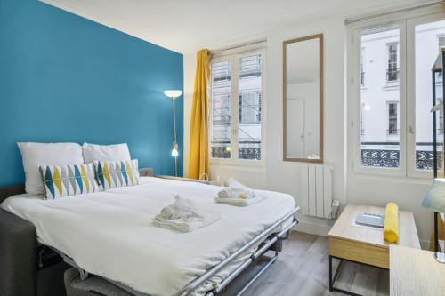 un grand lit blanc dans une pièce avec des fenêtres dans l'établissement 513 Suite Marie - Superbe logement Quartier Marais, à Paris